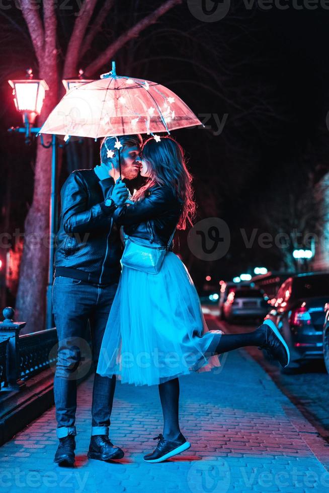 Guy and girl kissing under an umbrella photo