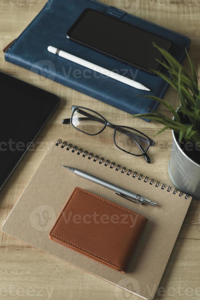 Workplace Desktop home office. Top view of table, laptop, glass, documents, tablet, business card, purse, calculator, pen, books,coffee. Business background, organization. photo