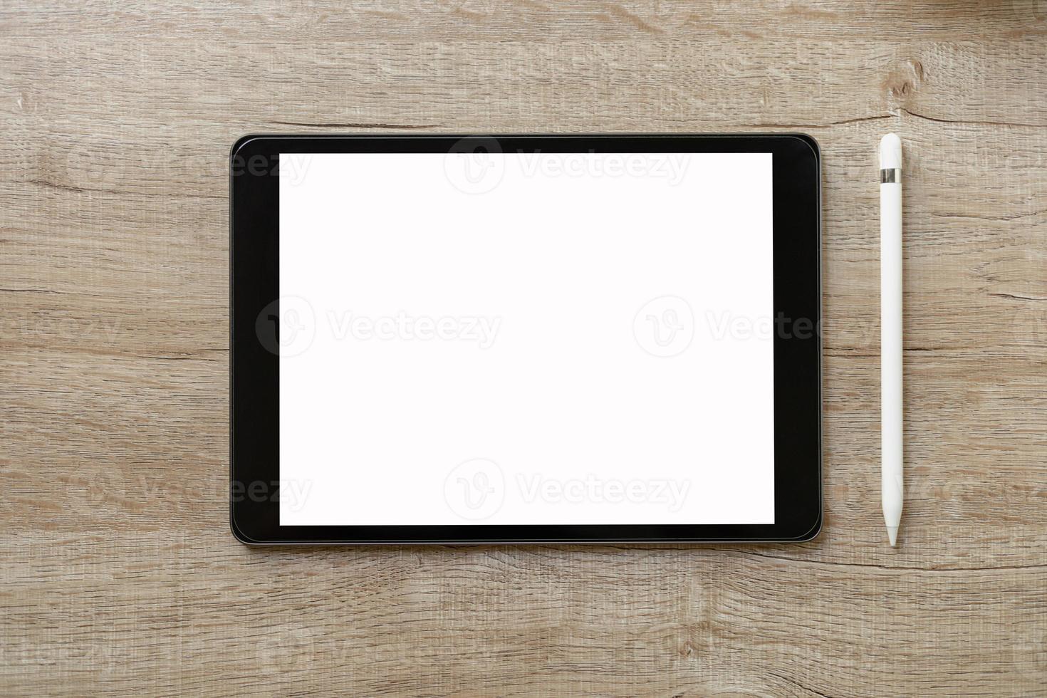 Black tablet with white blank screen is on top of brown paper with supplies. Top view, flat lay. photo