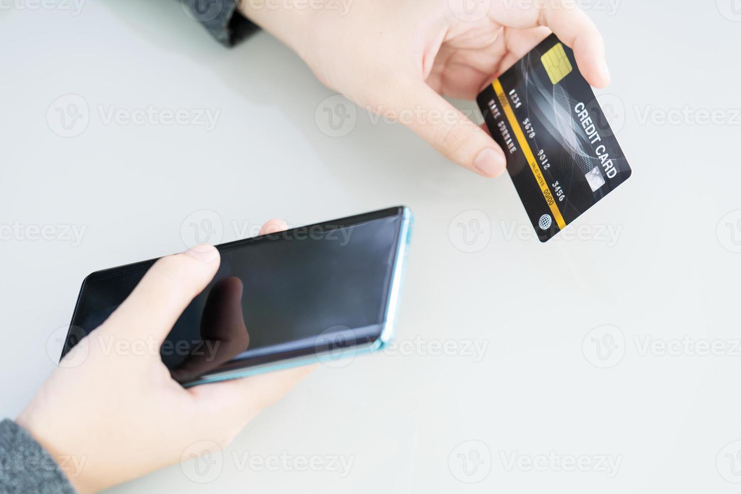 mano de mujer con tarjeta de crédito y uso de teléfono celular para compras en línea foto