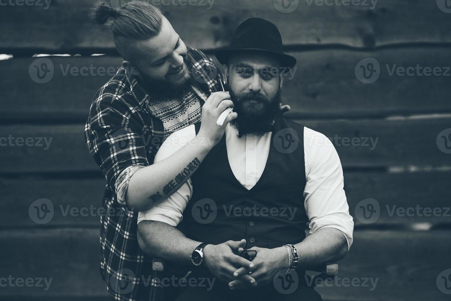 barbero afeita a un hombre barbudo foto