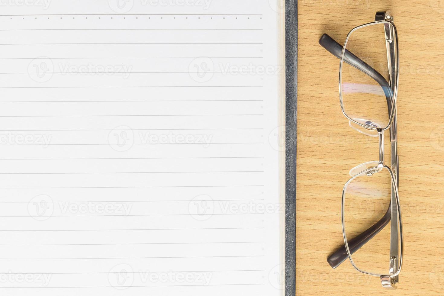 Notebook open blank page and eyeglasses photo
