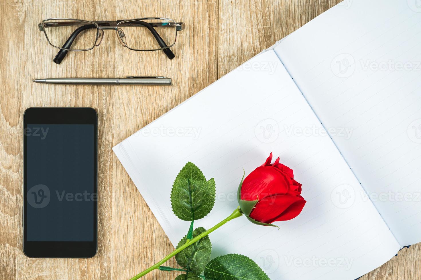 rosas rojas en el diario del cuaderno en blanco con el concepto de San Valentín del teléfono inteligente foto