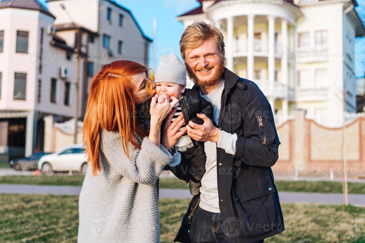 happy mom dad and son hugging in the park photo