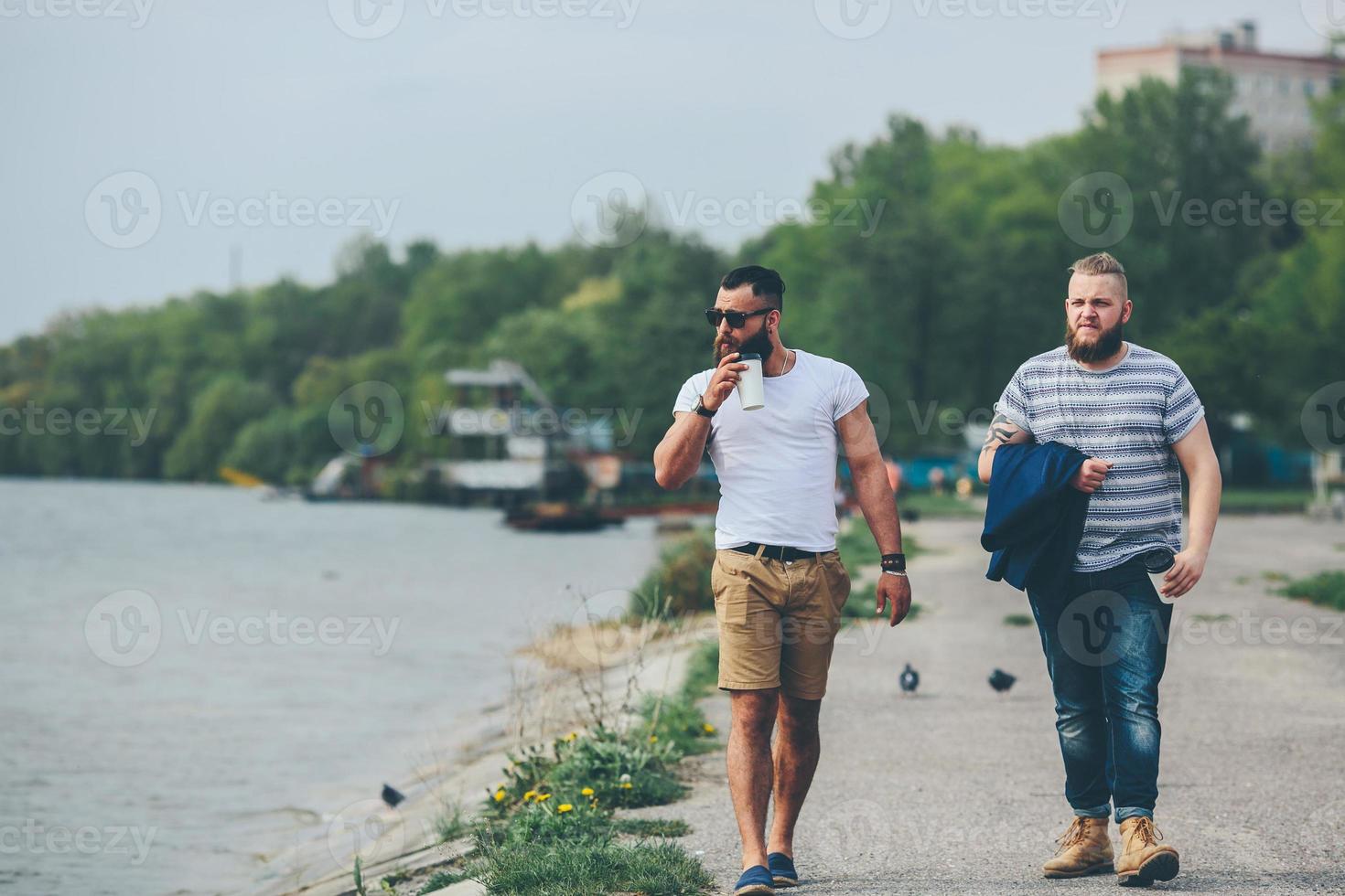 Two men walk and drink coffee photo