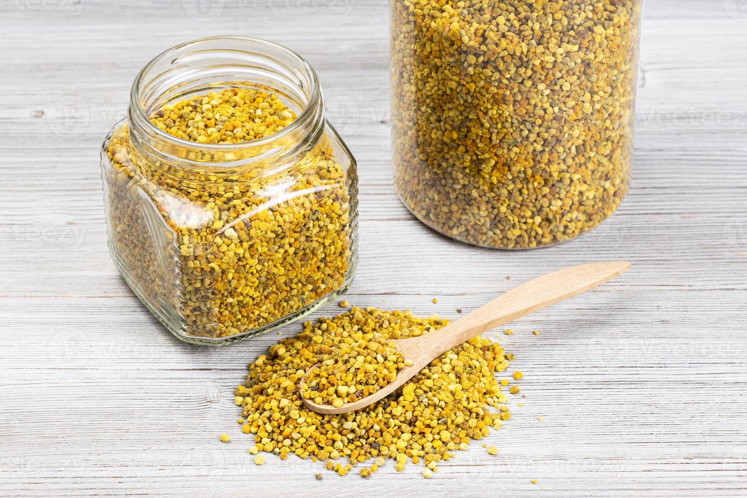 spoon in pile of bee pollen near jars on gray photo