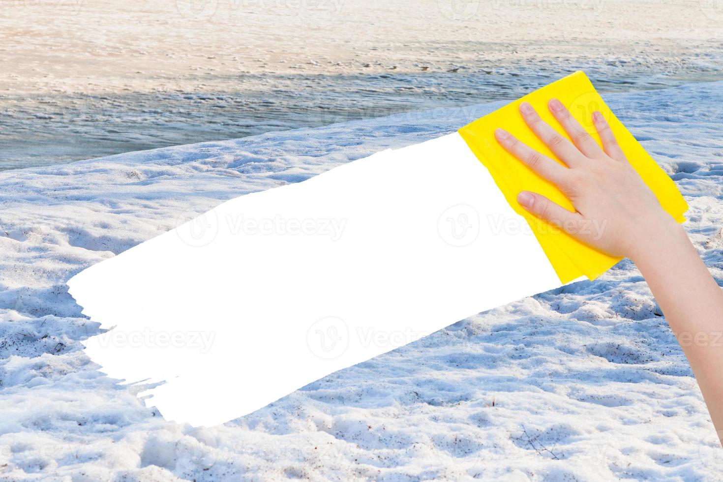 hand deletes white snow by yellow rag photo