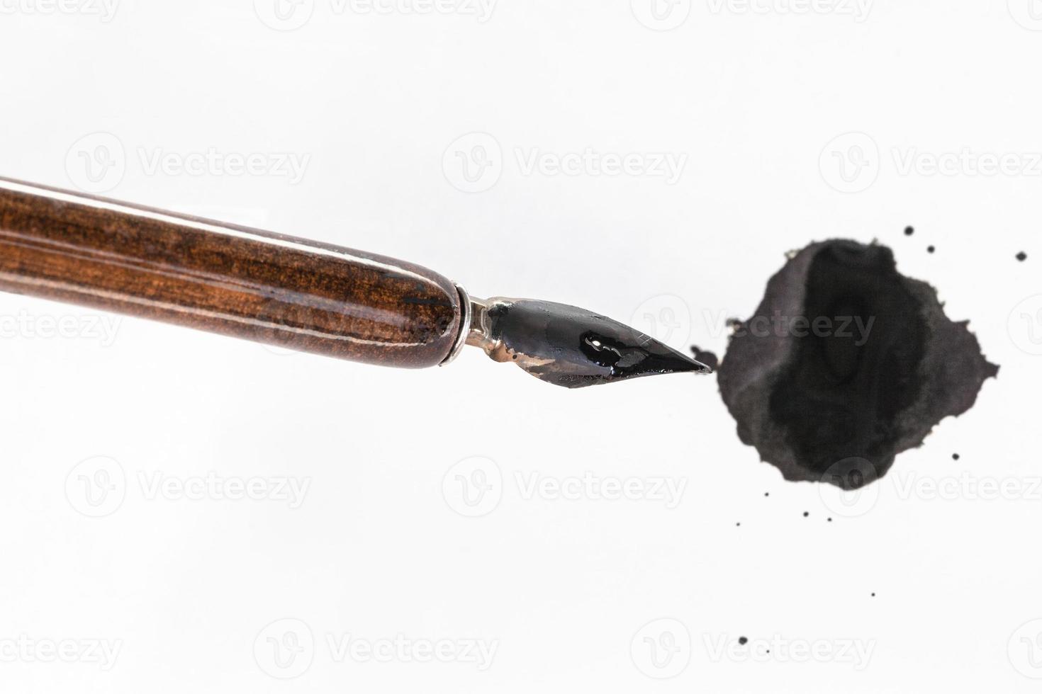 black painted nib of brown penholder over ink blot photo