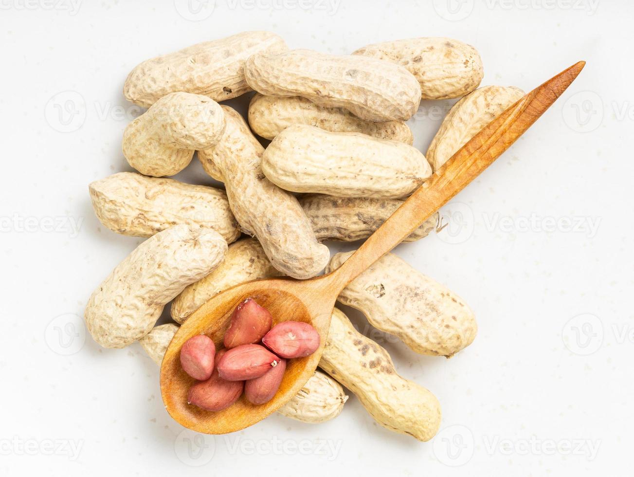 top view of cores in spoon and pile of peanuts photo