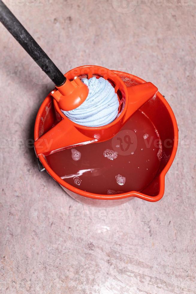 top view of squeezing mop in red bucket at home photo