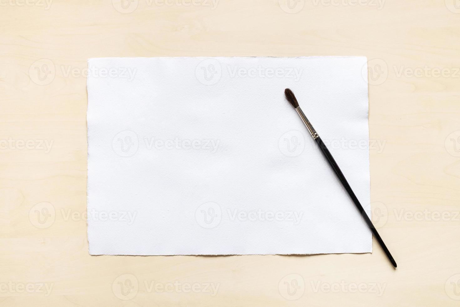 paintbrush and blank sheet of white textured paper photo