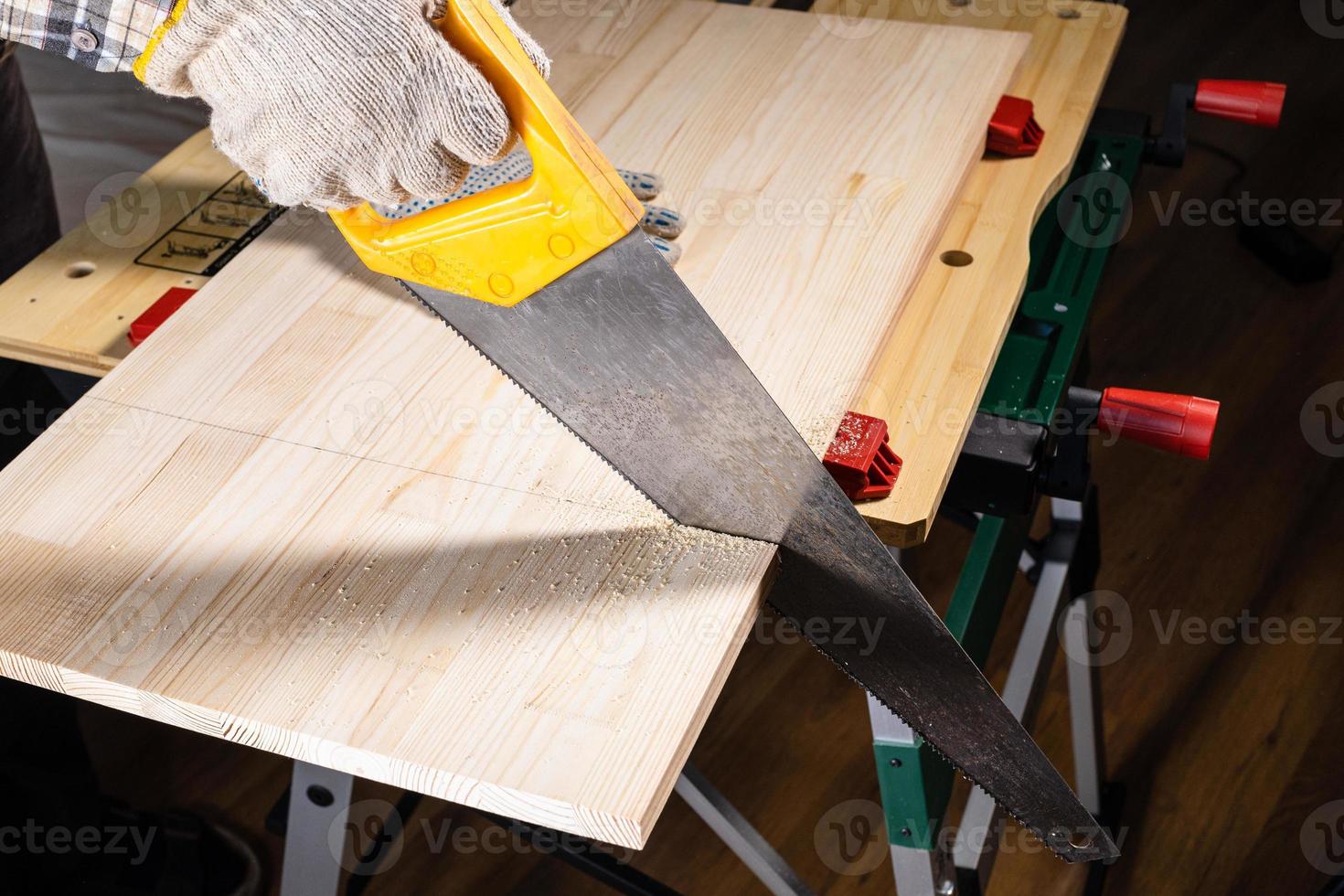 woodworker saws wooden board with hand saw photo