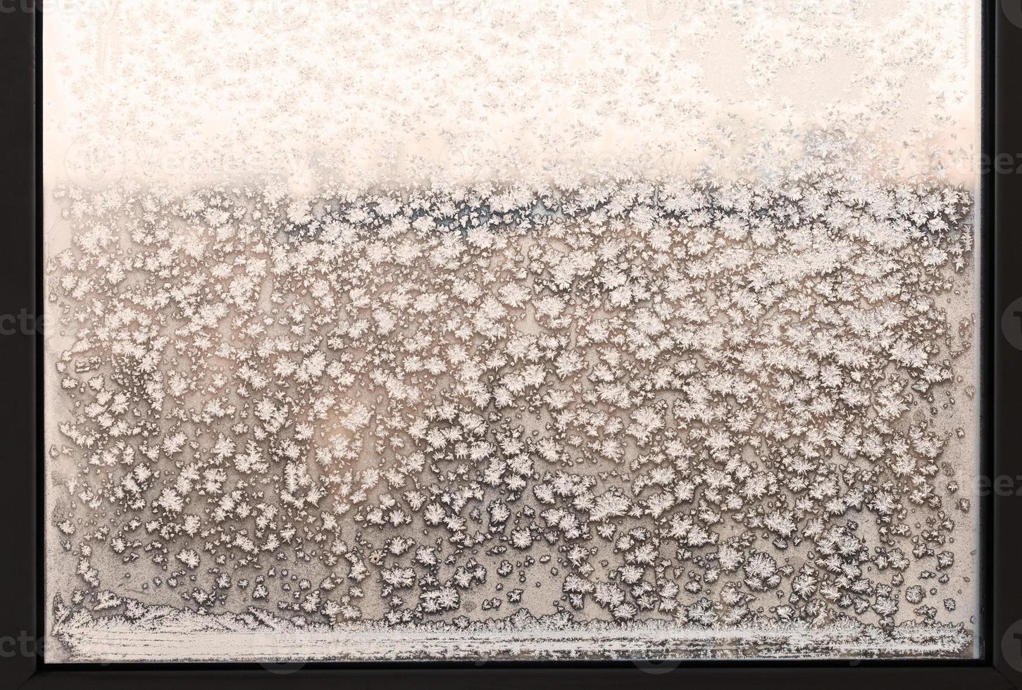 snowflakes and frost pattern on frozen home window photo