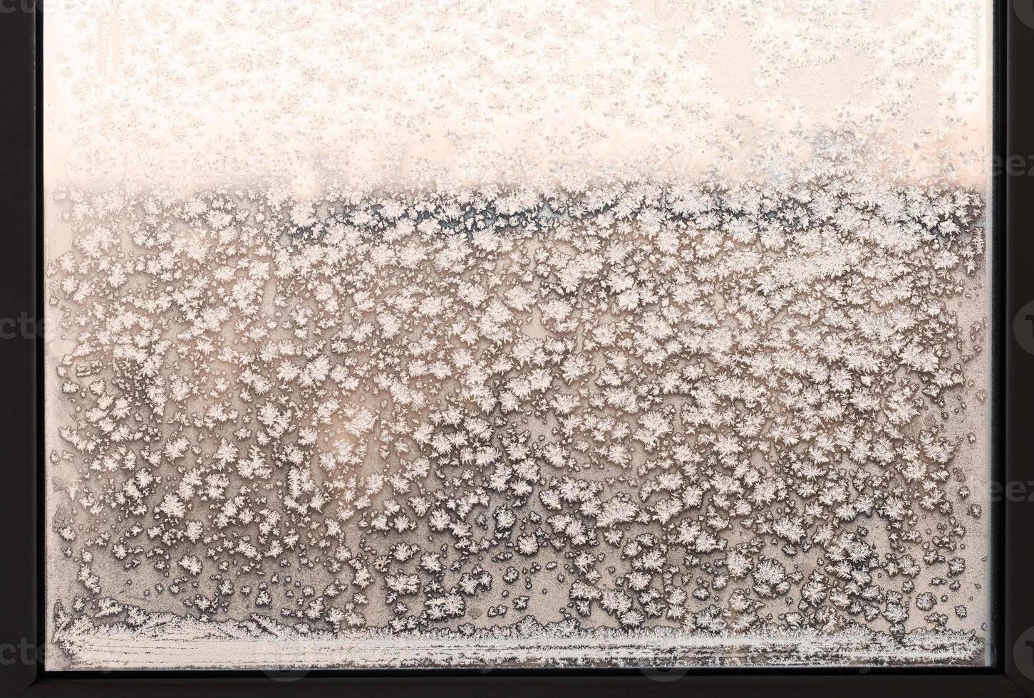 copos de nieve y patrón de escarcha en la ventana de casa congelada foto