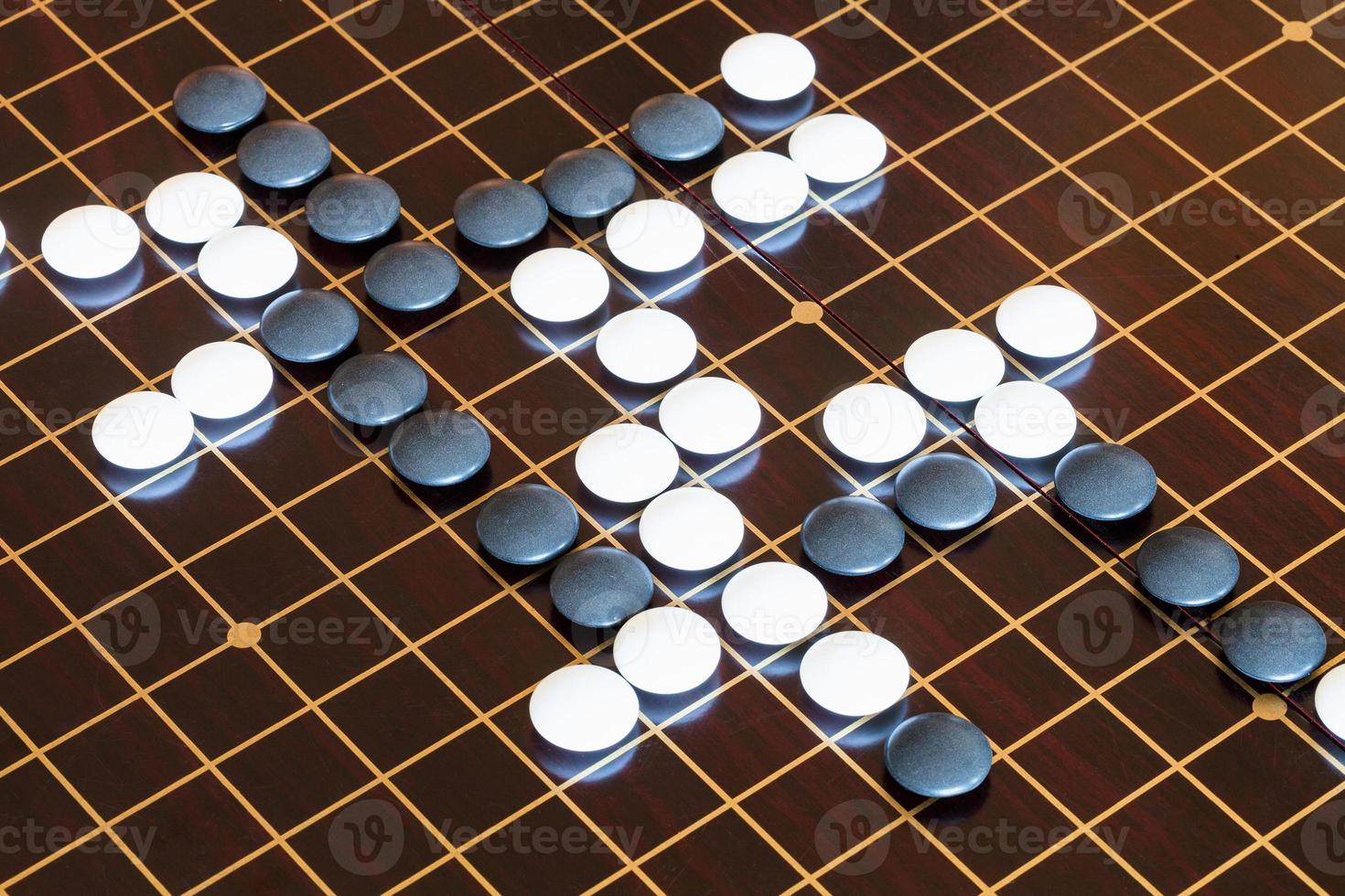 playing stones on wooden board in Go photo