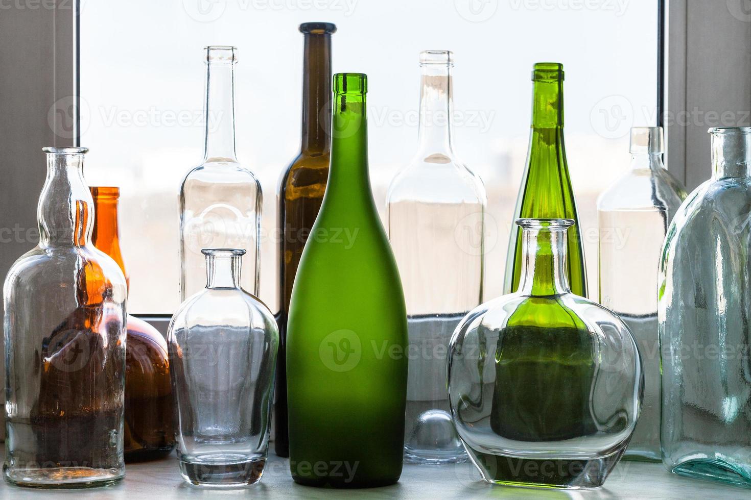 varias botellas vacías en el alféizar de la ventana en casa foto