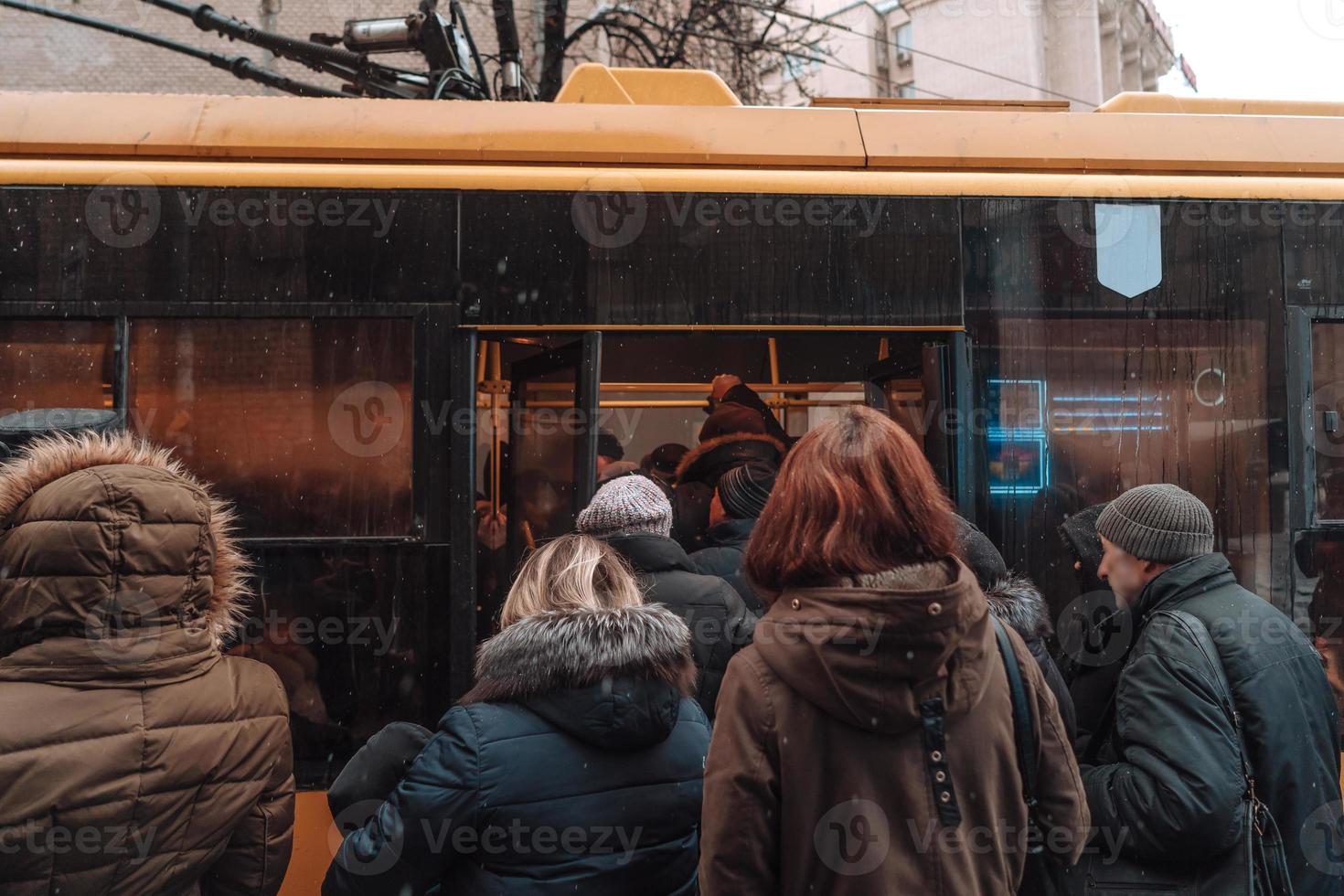 Many unidentified people are waiting for city transport at the bus stop photo