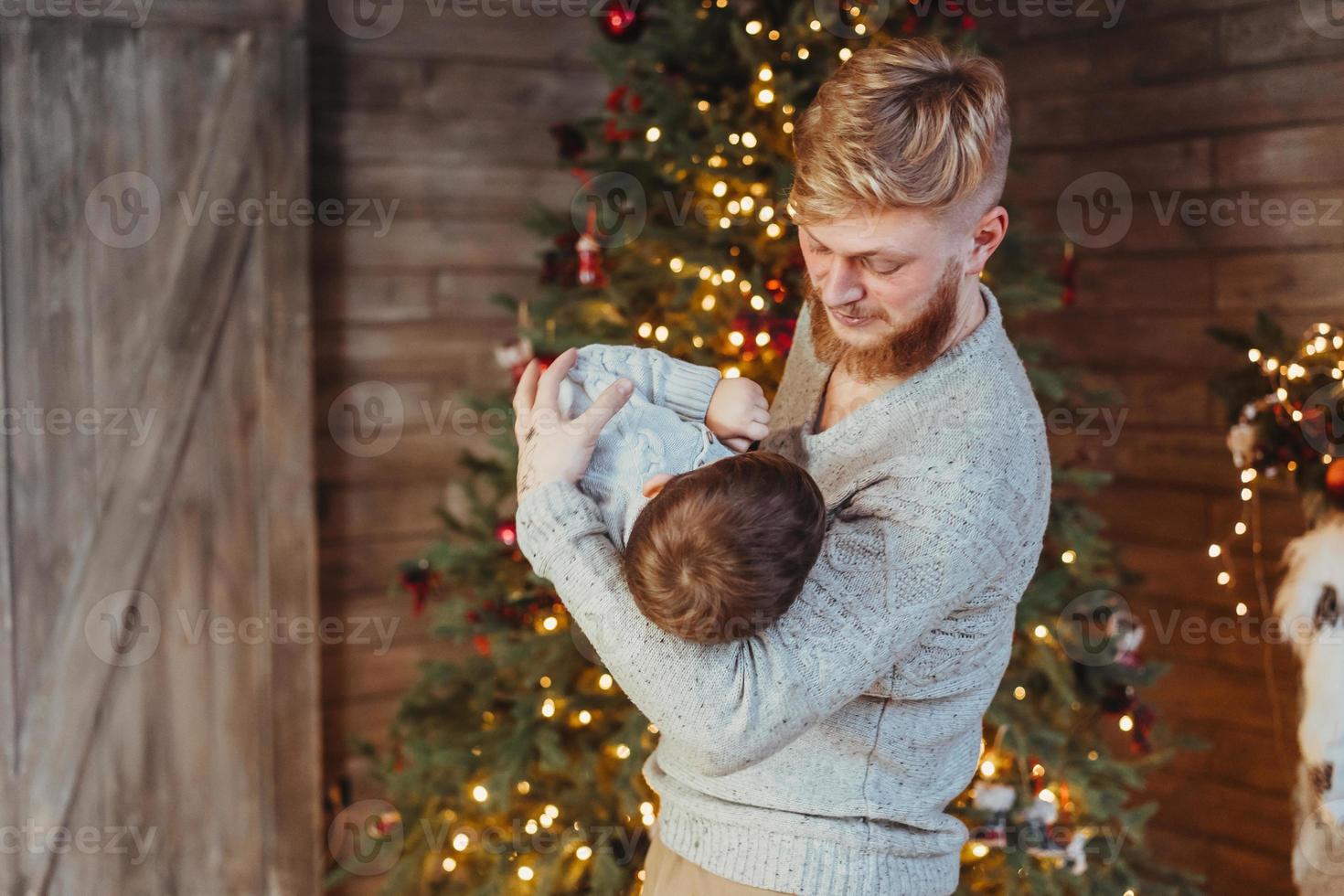 Handsome hipster father with small baby.Christmas background with light photo