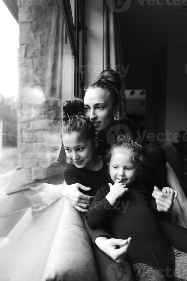 mamá y dos hijas juntas en la ventana foto