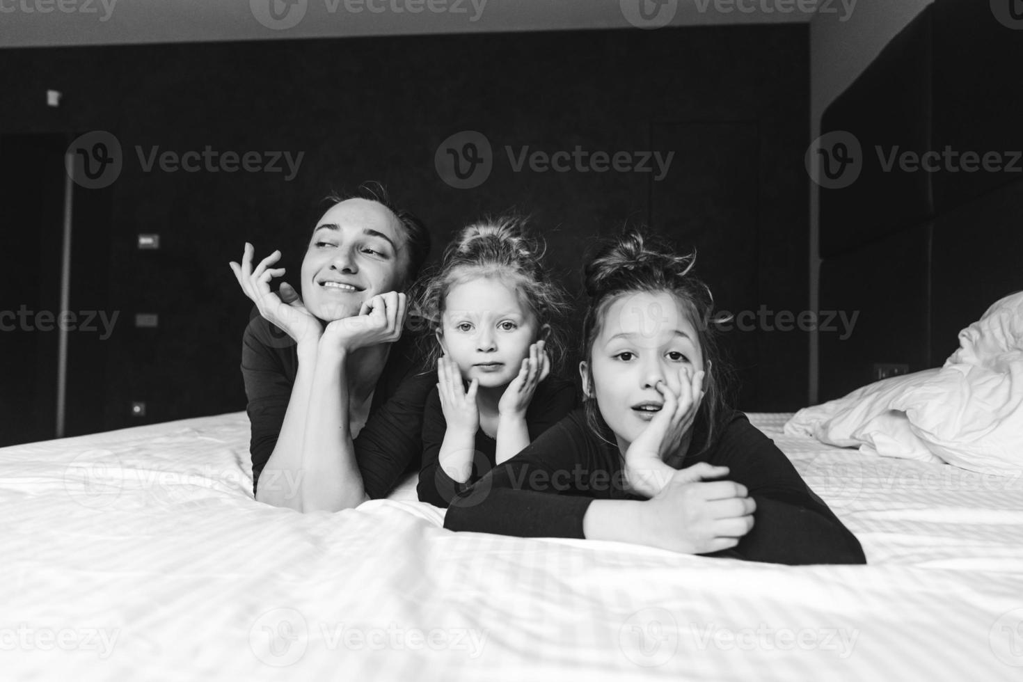 Mom and two daughters have fun on the bed photo