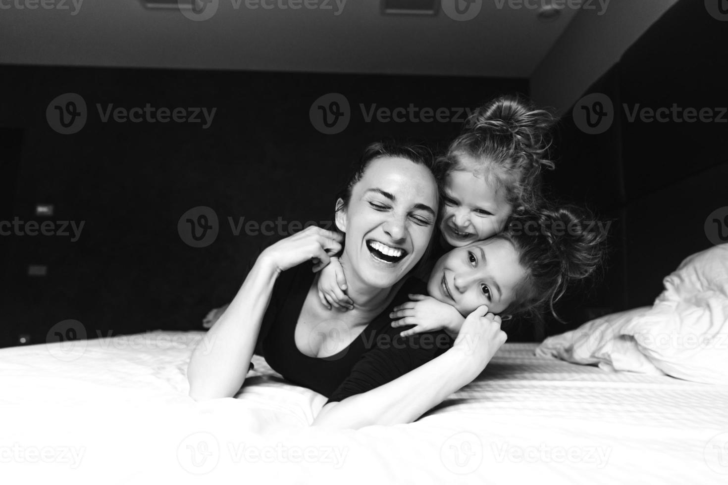 Mom and two daughters have fun on the bed photo