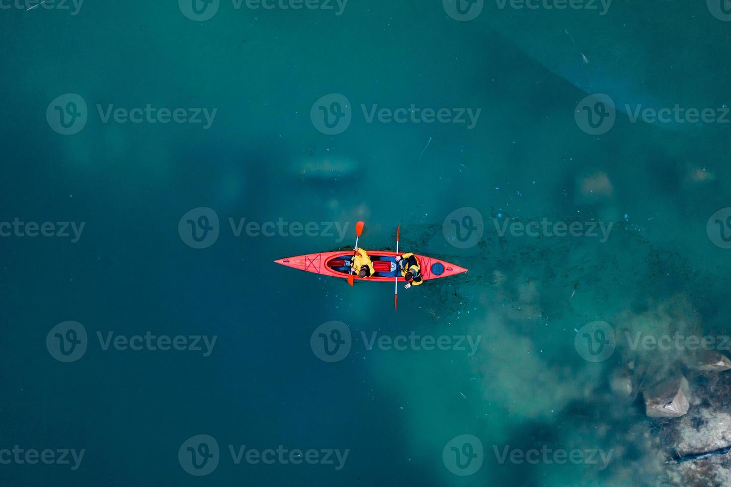 two athletic man floats on a red boat in river photo