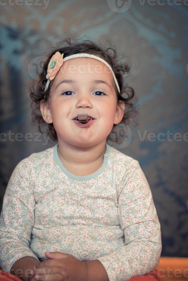 Sweet little girl with eating chocolate. photo