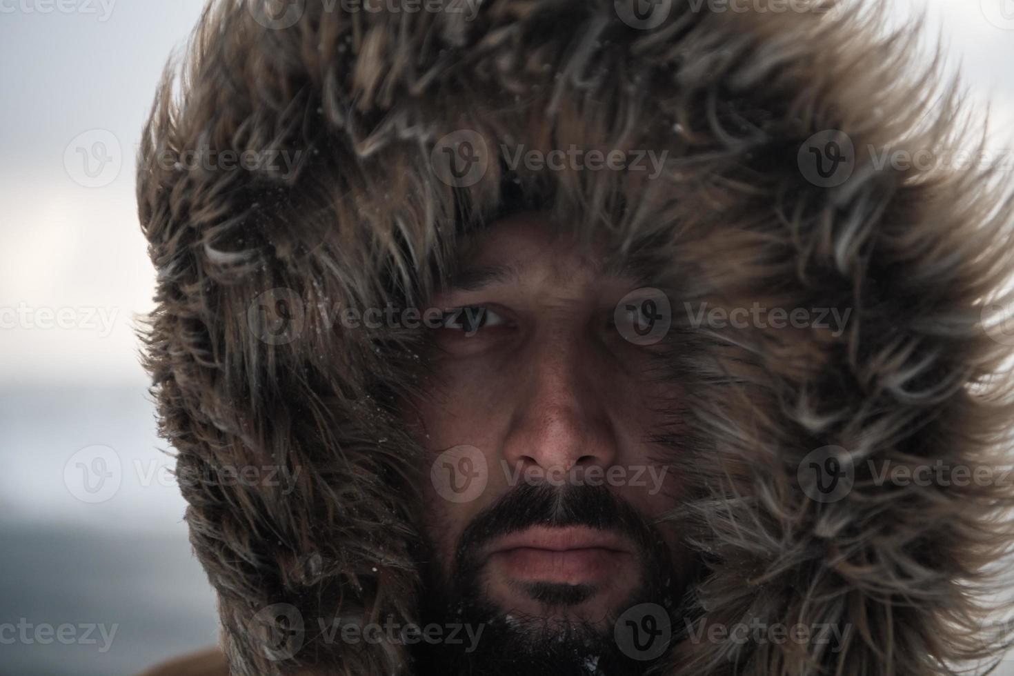 man at winter in stormy weather wearing warm  fur jacket photo