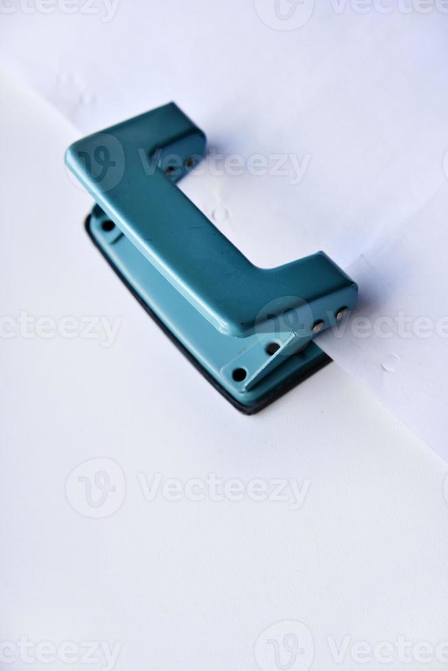 A white stapler and a green hole punch on a white background. Stationery on a white background. photo