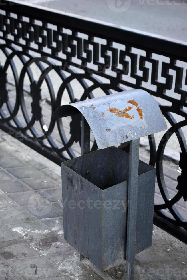 un basurero de hierro en una gran ciudad en verano. cubo de basura en la calle de la ciudad. foto