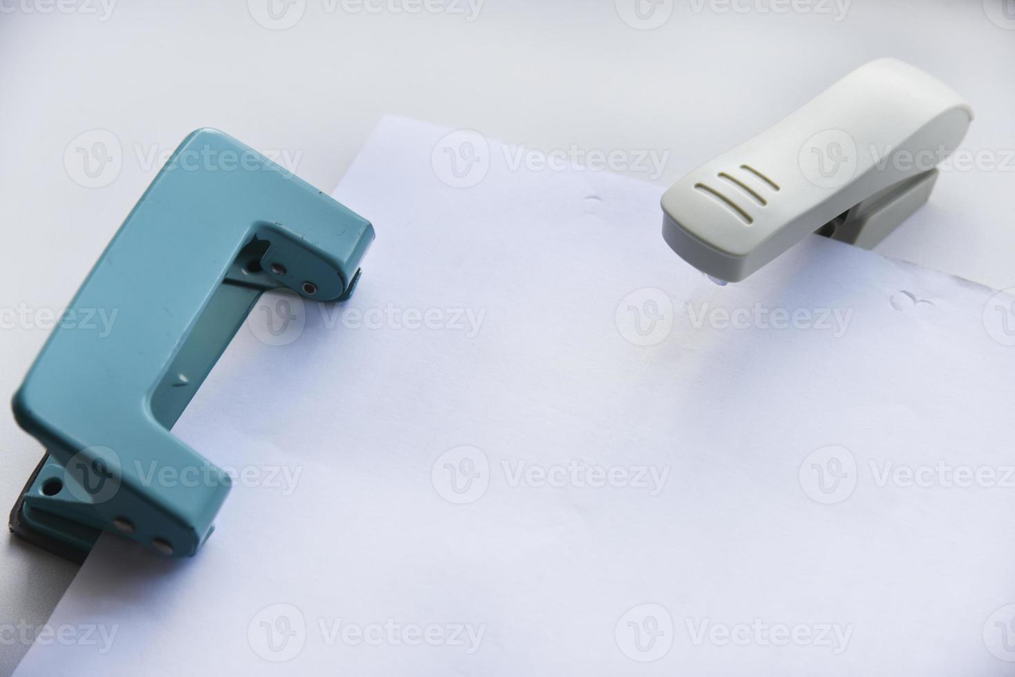 A white stapler and a green hole punch on a white background. Stationery on a white background. photo
