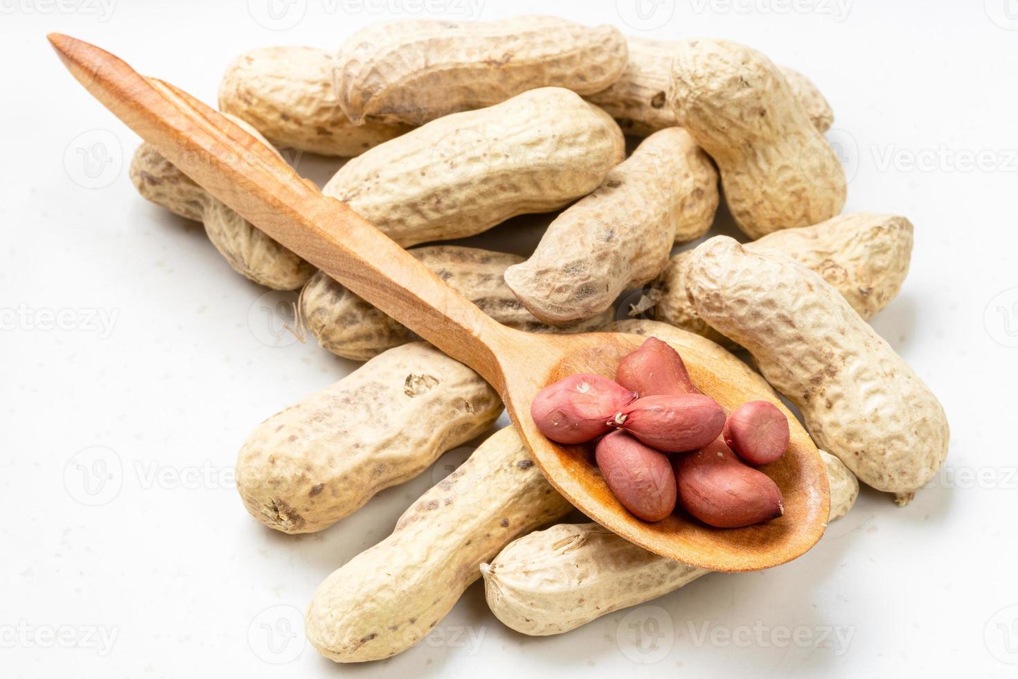 cores in wood spoon and pile of peanuts on gray photo