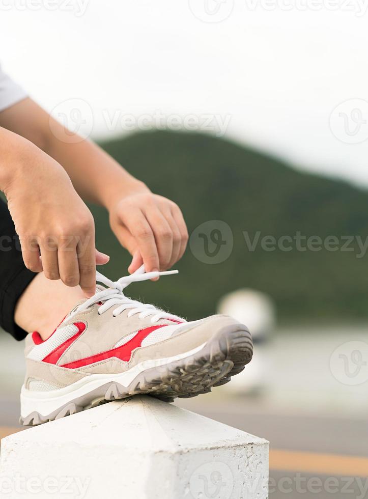 Woman tying shoelace his before starting running photo