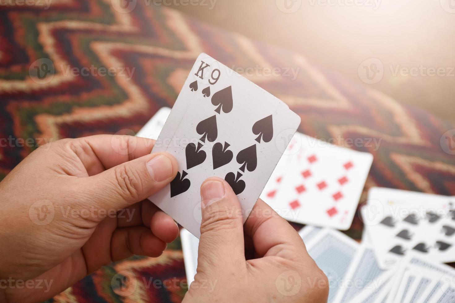 Paper cards number 9 and King holding in hands of woman who sitting and playing card with friend, soft and selective focus, freetimes and hobby activity at home concept. photo