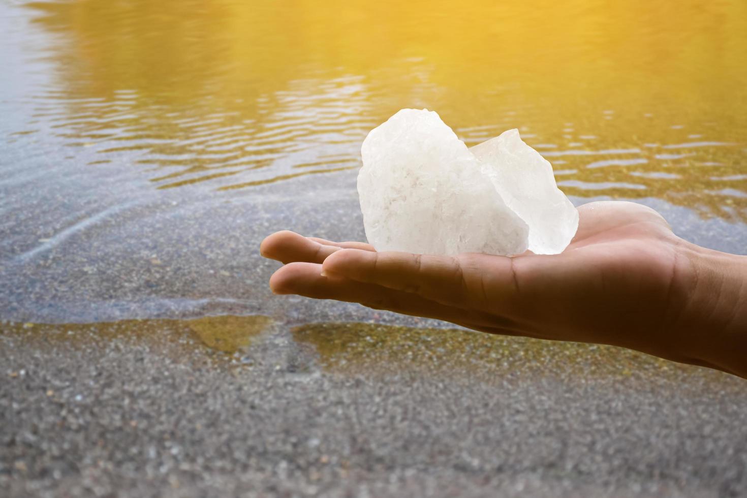 White alum bar holding in hand with cloudy water, concept for using alum to sway or swing the cloudy water to be clean and clear before using it in human daily life, soft and selective focus. photo