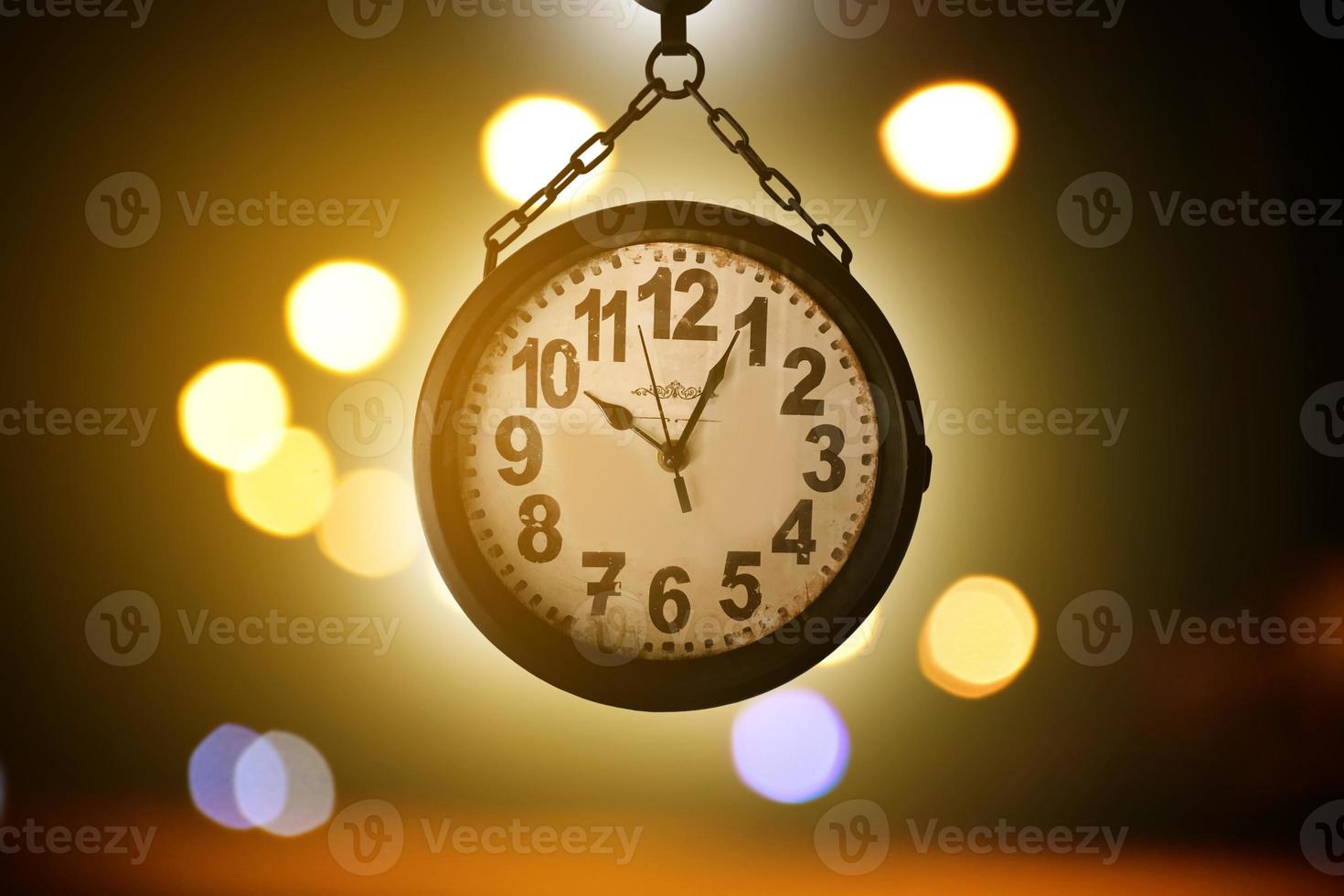 Closeup vintage hanging clock, blurred street light bokeh background, soft and selective focus on clock. photo