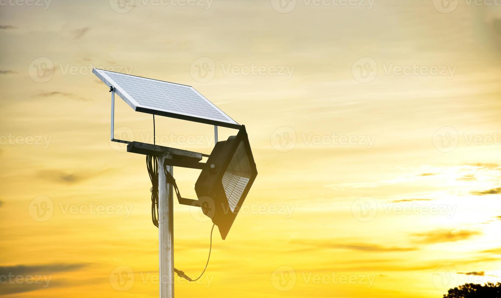 Mini solar or photovoltaic cell panel installed on metal pole with floodlight led, blurr cloudy and bluesky background, concept for using natural energy from the sun in daily life of human. photo