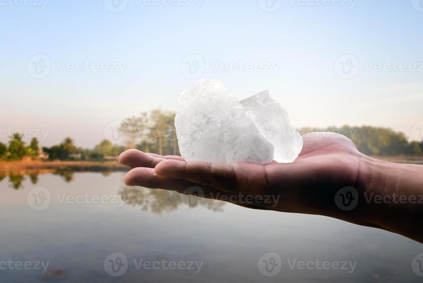 White alum bar holding in hand with cloudy water, concept for using alum to sway or swing the cloudy water to be clean and clear before using it in human daily life, soft and selective focus. photo