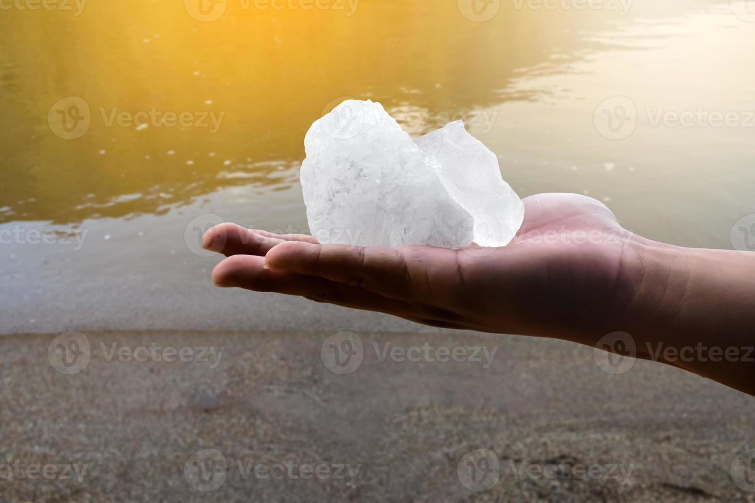 White alum bar holding in hand with cloudy water, concept for using alum to sway or swing the cloudy water to be clean and clear before using it in human daily life, soft and selective focus. photo