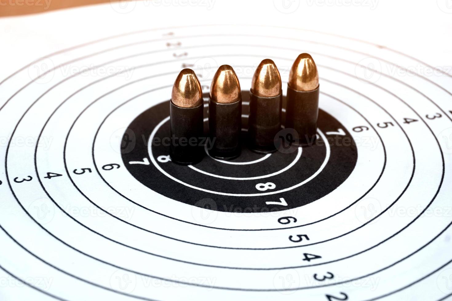 Balas de pistola de 9 mm en papel de tiro al blanco, enfoque suave y selectivo foto