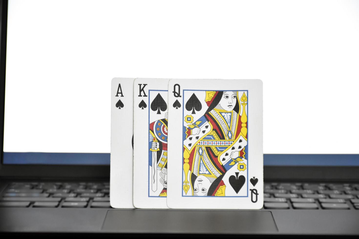 Paper cards on blank laptop keyboard, soft and selective focus, concept for playing cards online with other people at home and recreational activity. photo