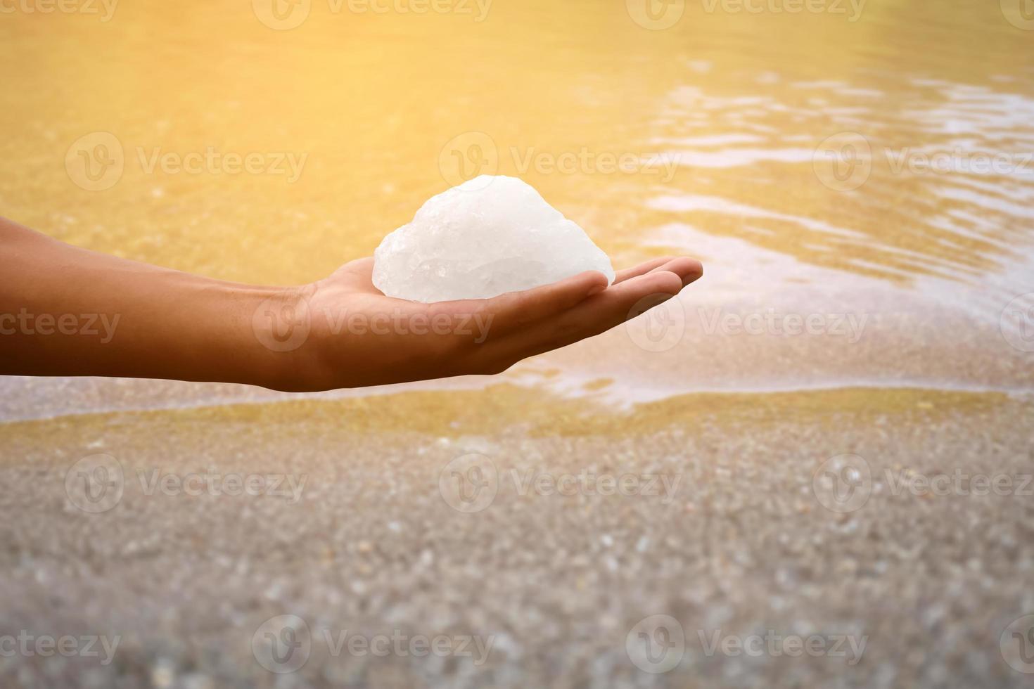 White alum bar holding in hand with cloudy water, concept for using alum to sway or swing the cloudy water to be clean and clear before using it in human daily life, soft and selective focus. photo