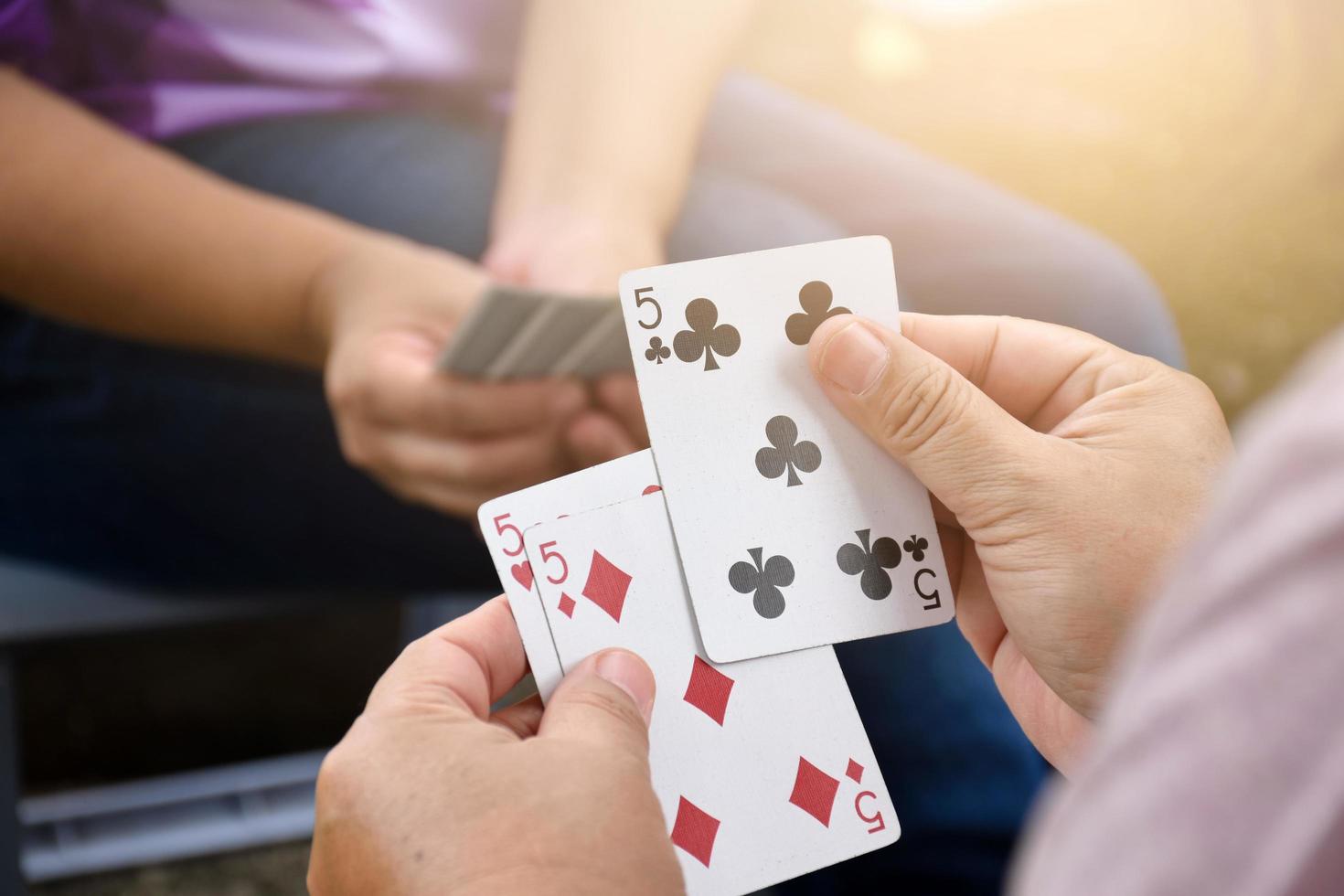 Paper cards number 5 holding in hands of woman who sitting and playing card with friend, soft and selective focus, freetimes and hobby activity at home concept. photo