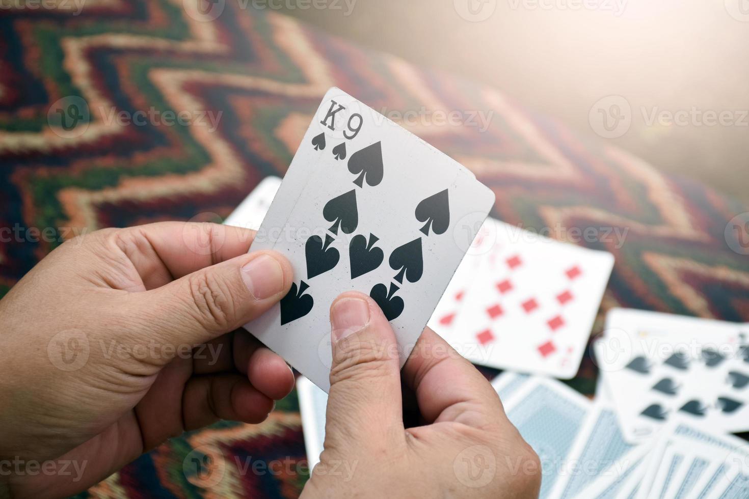 Paper cards number 9 and King holding in hands of woman who sitting and playing card with friend, soft and selective focus, freetimes and hobby activity at home concept. photo