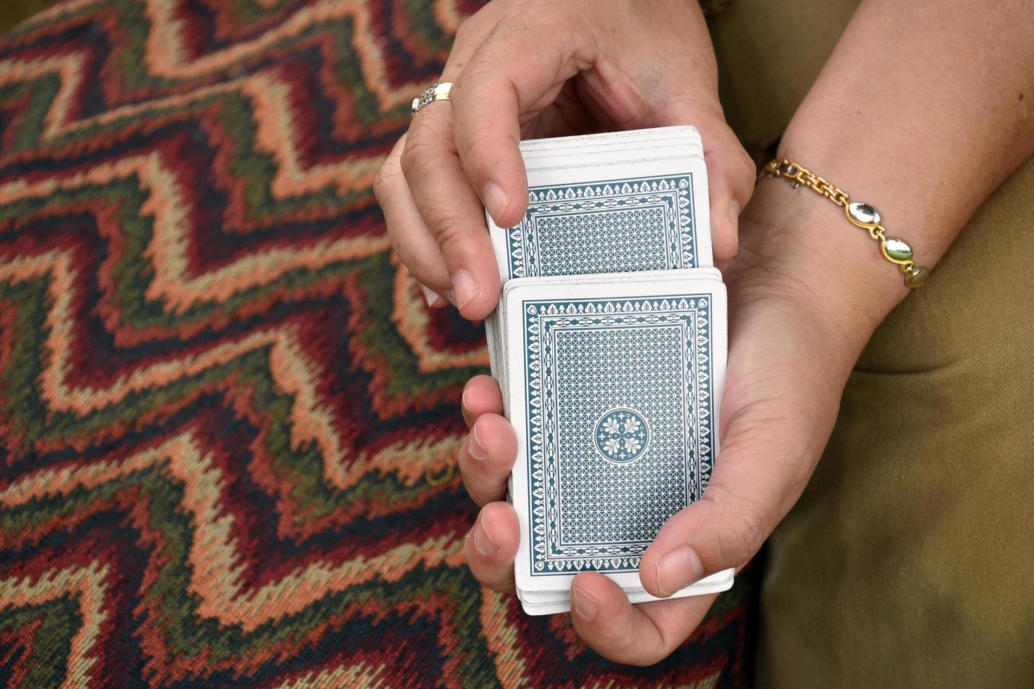 Paper cards number 5 holding in hands of woman who sitting and playing card with friend, soft and selective focus, freetimes and hobby activity at home concept. photo