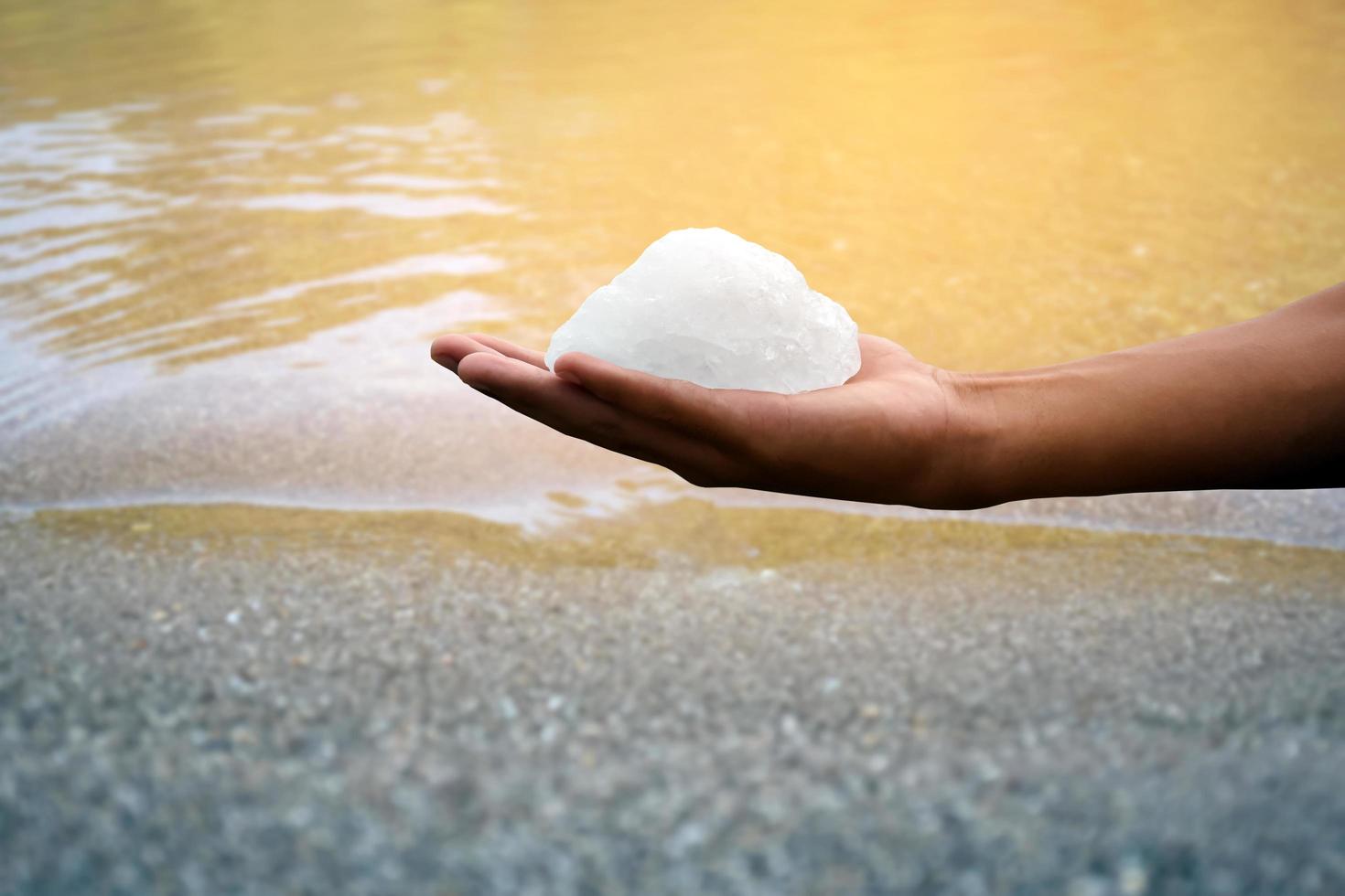 barra de alumbre blanca sosteniendo en la mano con agua turbia, concepto para usar alumbre para balancear o balancear el agua turbia para que esté limpia y clara antes de usarla en la vida diaria humana, enfoque suave y selectivo. foto