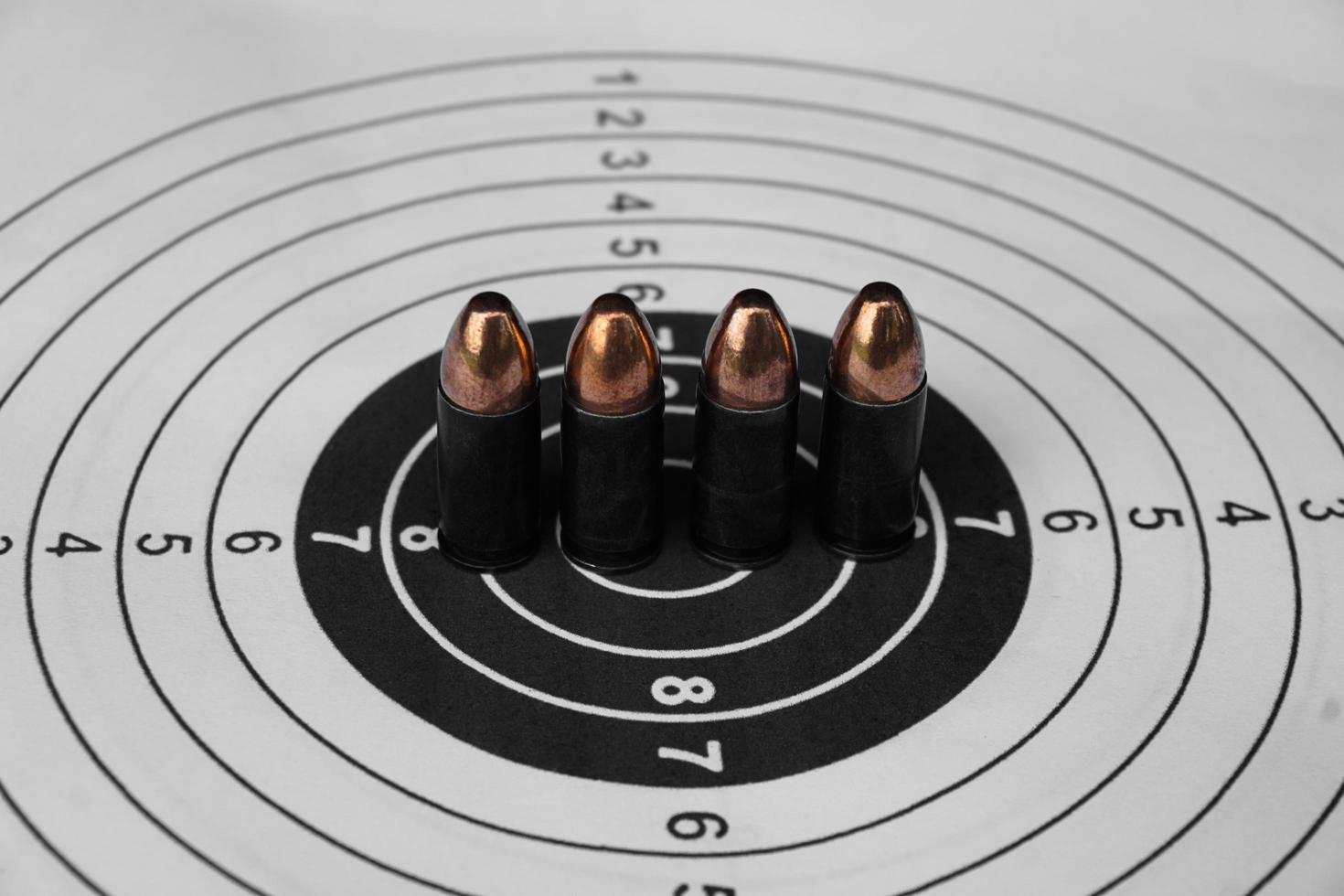 Balas de pistola de 9 mm en papel de tiro al blanco, enfoque suave y selectivo foto