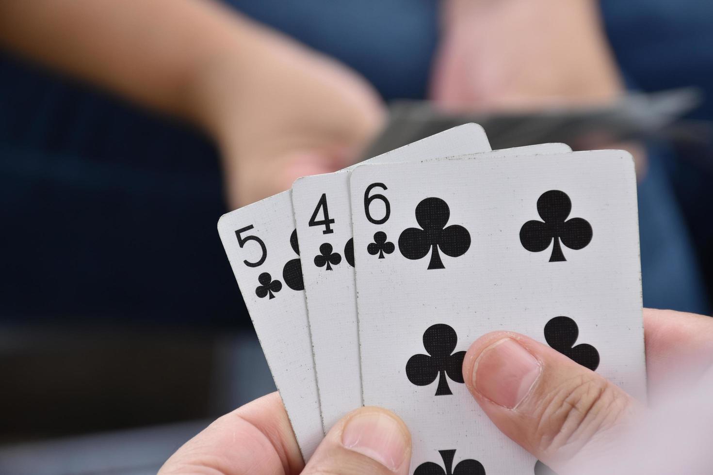 Paper cards number 5 holding in hands of woman who sitting and playing card with friend, soft and selective focus, freetimes and hobby activity at home concept. photo