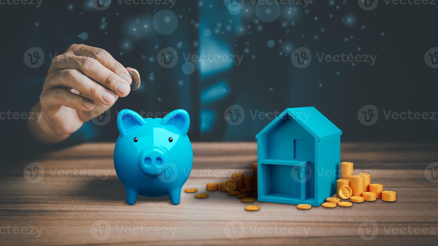 Man hand putting money coin into blue piggy bank for saving money, concept of saving to buy a house, real estate or home. photo