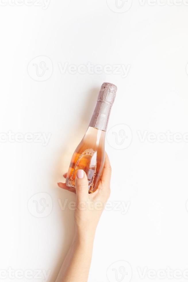 botella de vino de champán rosado en mano de mujer foto